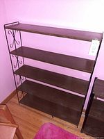 Front view of metal and wood bookshelf showing four shelves and scroll side design