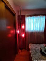 Full view of floor-to-ceiling tension pole lamp beside window and bed