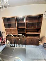 Front view of the full three-section wall unit beside dining chairs