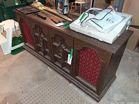 Front view of walnut stereo console showing red speaker grilles and cabinet doors