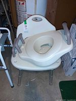 Raised toilet seat with arms placed on shower bench