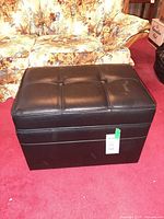 Front view of black bicast leather storage bench showing tufted lid and overall condition