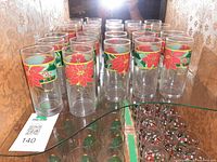 Front view of all twelve Hazel Atlas poinsettia tumblers arranged on shelf