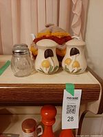 Lot overview showing clear glass shaker, pair of mushroom shakers, teapot with crochet cover