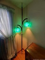 Full view of tension pole lamp with two lit blue lucite globes