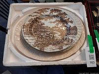 Stack of platters in foam, top Alfred Meakin Coaching Days scenic plate visible