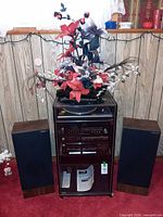 Full setup with cabinet, components, speakers, floral arrangement
