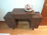 Closed wooden sewing cabinet with organizer on top, front view