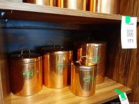 Front view of all four copper canisters on shelf