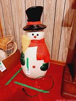 Full view of blow-mold snowman with hat, scarf, mittens, broom and cord
