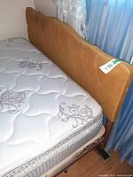 Queen bed showing mattress, box spring and mustard yellow upholstered headboard