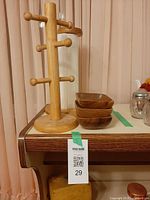 Wood mug tree, paper towel holder behind, stack of three bowls on tabletop