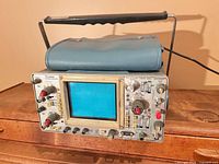 Front view showing Tektronix 465 oscilloscope, screen, controls, handle, cover