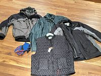 Four jackets, heated vest and gloves displayed on floor
