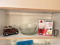 Lot overview showing egg cooker box, glass bowl with plates, firetruck holder with shakers, stacked egg cups