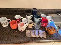 Overview of all mugs, teapot and coasters on countertop