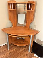 Full view of corner wood veneer desk with hutch and glass panels, lower shelf and TV on surface