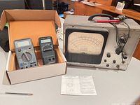 Overall view of three testers, cardboard box, instruction sheet, and EICO meter with leads