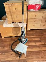Steam mop assembled and standing upright in front of dressers