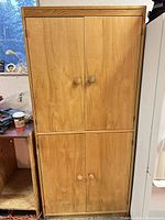 Full view of the light wood cabinet with four doors and round knobs