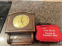 Front view of wall clock beside first aid kit