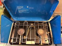 Stove open showing two burners, grate, and lid interior