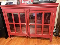Front view of red cabinet showing glass-panel doors and handles