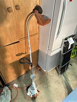 Full view of Stihl FS 38 gas trimmer leaning against cabinet and refrigerator