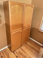 Front view of stacked oak-finish pantry cabinet showing four doors