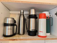 Five thermoses arranged on shelf