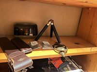 Shelf view showing tripod, vacuum tubes in tin, slide rule sleeves and small accessories