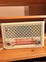 Front view of cream Bakelite Philips Aviso valve radio showing lattice grille, tuning scale, knobs, and power cord.