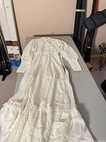 Full length view of white Victorian style wedding dress laid flat