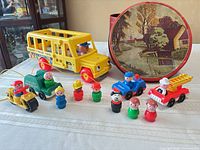 Group shot of bus, small vehicles, figures, and round tin