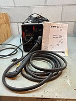 Front view of plasma cutter with torch cable and manual