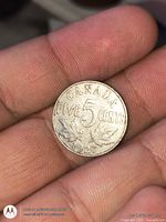 Reverse side of 1927 Canada 5-cent coin showing denomination and maple leaves
