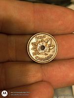 Front of drilled Canadian 1 cent coin showing maple leaf design and date 1940s