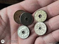 Five holed coins displayed on palm