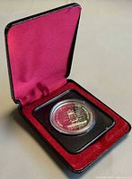 Coin in presentation case showing capsule and burgundy liner