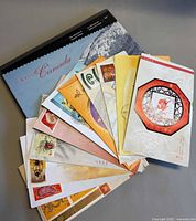 All items fanned out: hardcover slipcase beneath and approximately twelve colourful souvenir packs