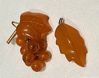 Both amber brooches front view showing leaf and berry designs