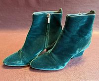 Side profile of both emerald green velvet ankle boots showing outer sides and toe shape