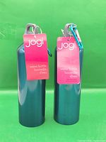 Front view of two teal Jogi stainless steel bottles with hang tags