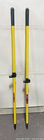 two yellow push broom handles standing upright