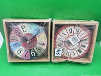 Both boxed wooden wall clocks side by side