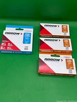 Four packs Arrow staples arranged on green backdrop