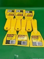 All six yellow adhesive spreaders arranged on green surface