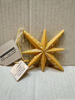 Front view of yellow eight-point star ornament with tags