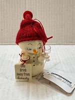 Front view of snowman ornament showing tag, glass, facial details