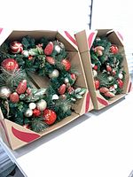 Two boxed pre-lit wreaths side by side